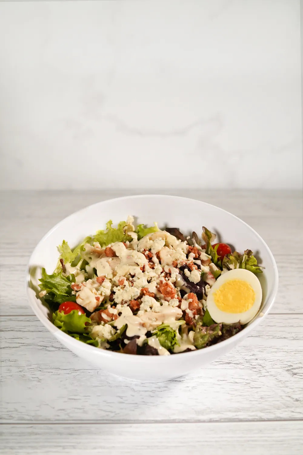 Salad with a hard boiled egg, creamy dressing and garnishes