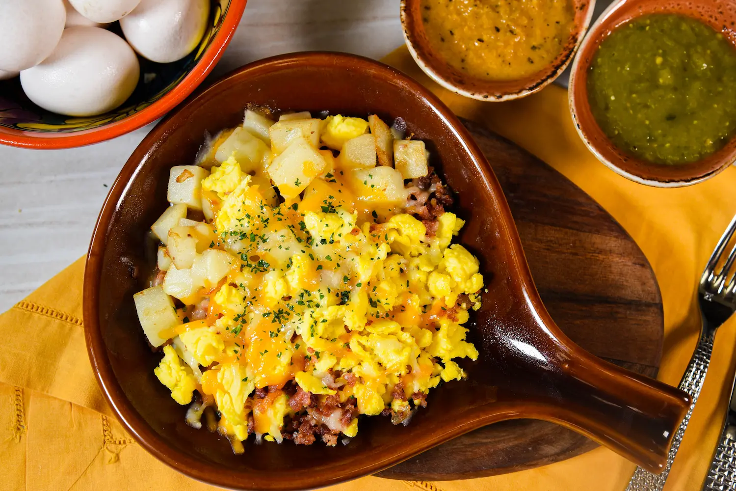 Cheese potatoes with yellow and green sauces on the side.